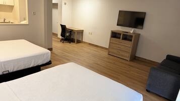 Habitación de hotel con dos camas, un escritorio, una silla, un televisor y un aparador.