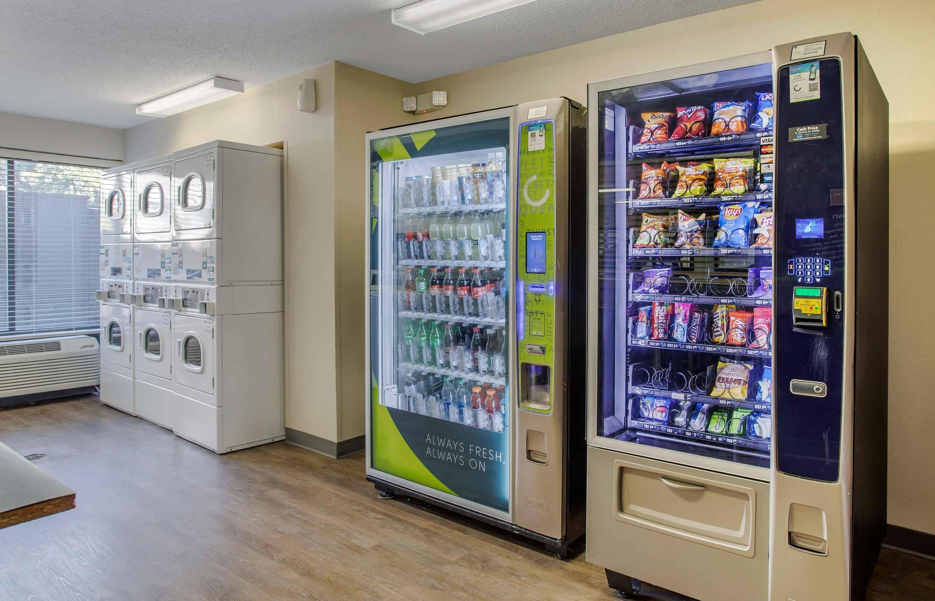 A hotel lobby with a row of self-service vending machines, including a water cooler and snack dispensers.