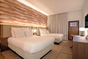 Habitación de hotel con dos camas, un escritorio, una silla y una puerta.
