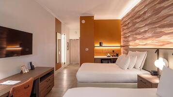 Una habitación de hotel con cama, mesita de noche, escritorio, silla y televisor.
