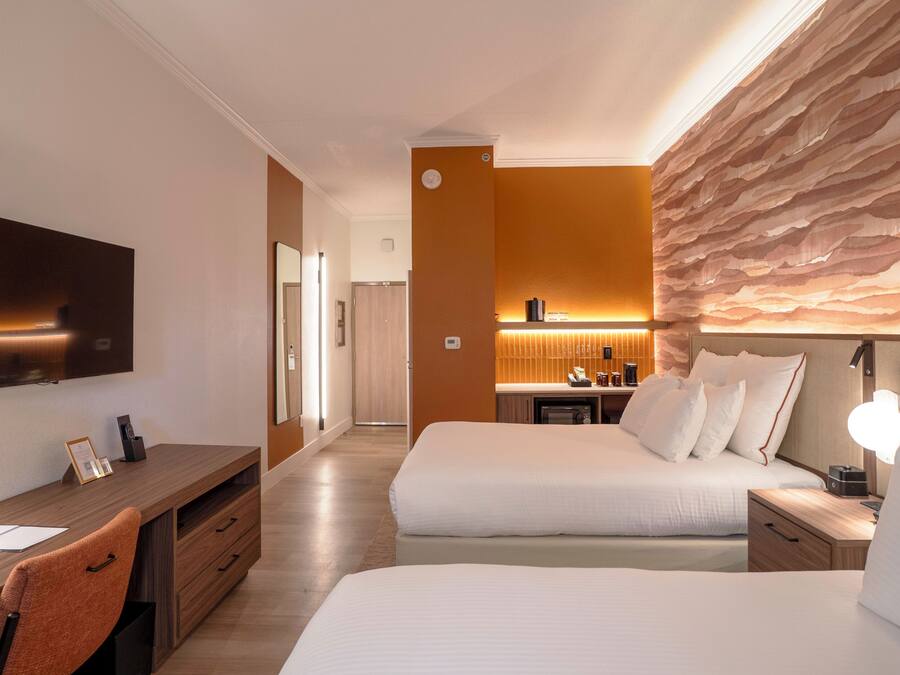 Una habitación de hotel con cama, mesita de noche, escritorio, silla y televisor.