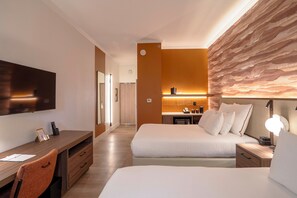 Una habitación de hotel con cama, mesita de noche, escritorio, silla y televisor.