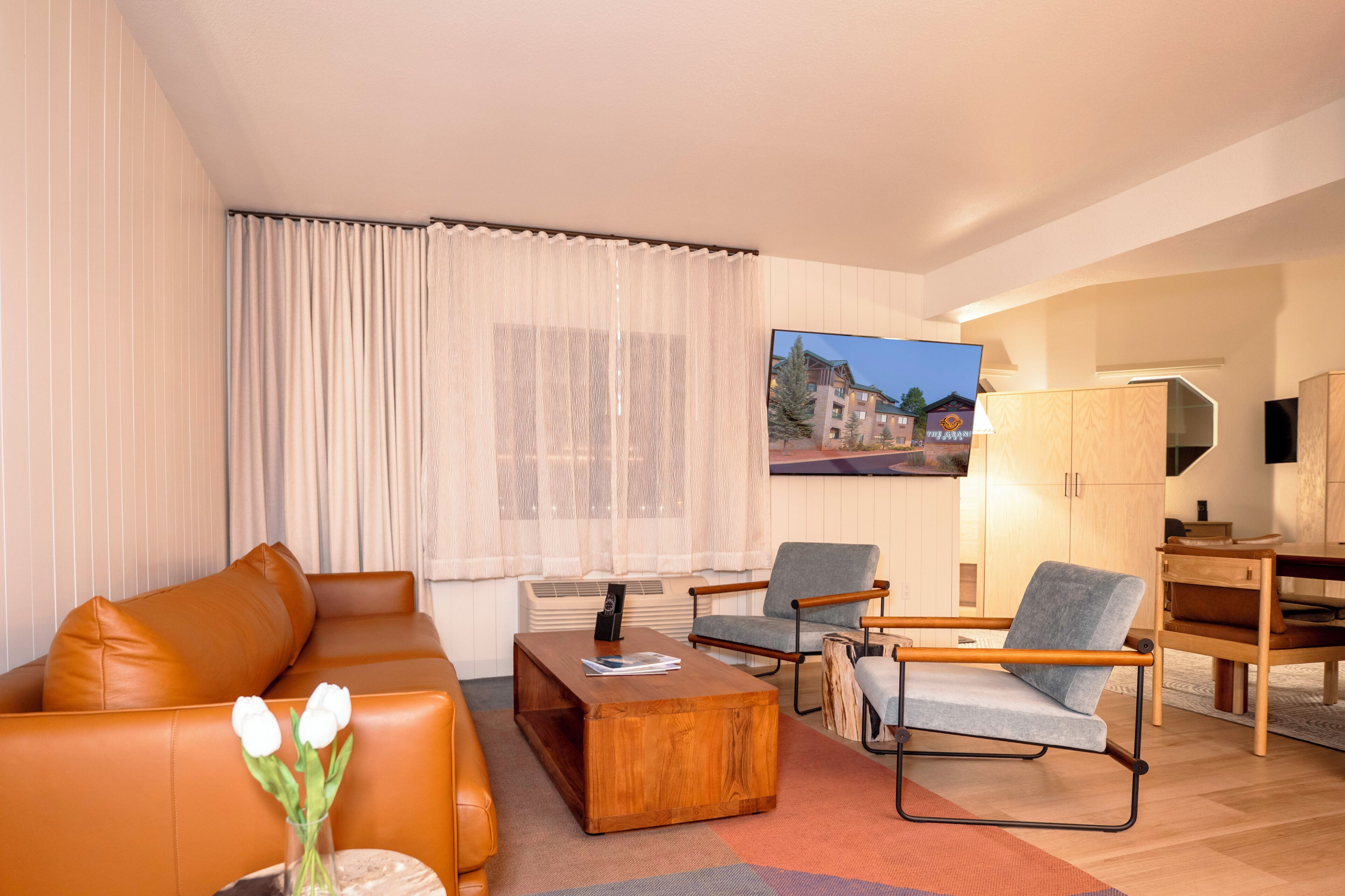 Een moderne woonkamer met een bank, stoelen, een salontafel en een televisie.