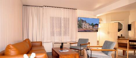 Una sala de estar moderna con un sofá, sillas, una mesa de centro y un televisor.
