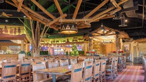 Un restaurant avec des tables et des chaises en bois, un sapin de Noël et un coin bar.