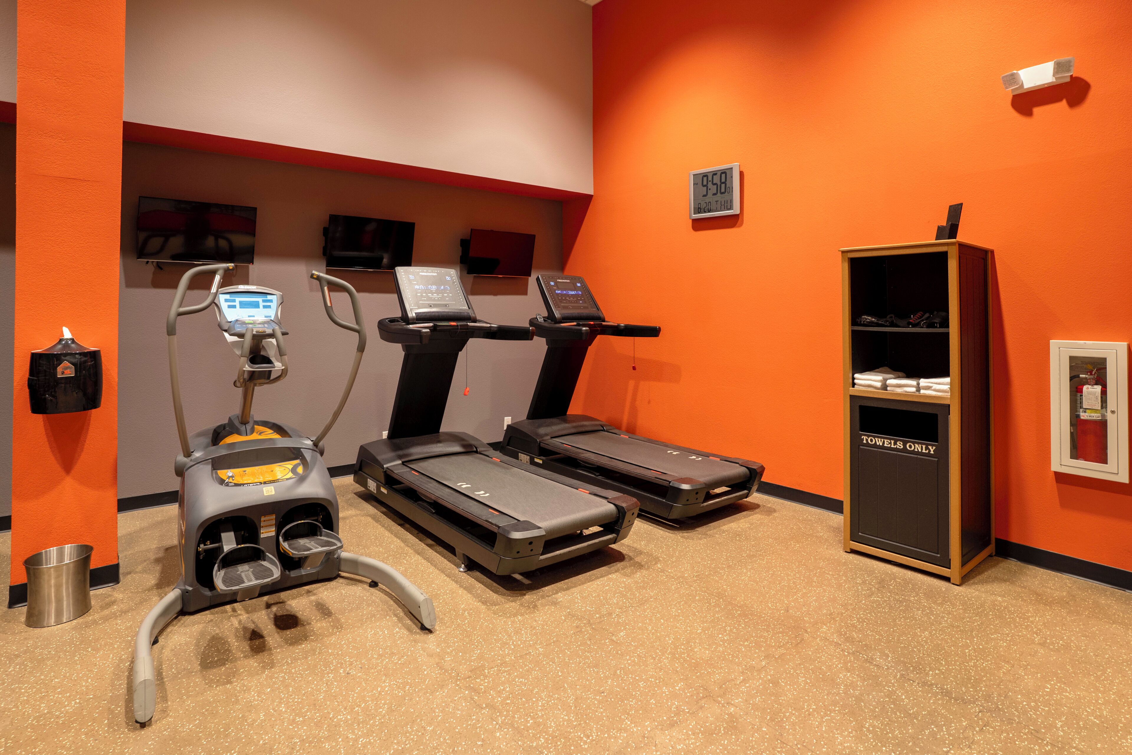 Ein Fitnessraum mit Laufbändern, einem Ergometer und einem Laufband mit digitaler Anzeige.