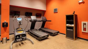 A fitness room with treadmills, a stationary bike, and a treadmill with a digital display.