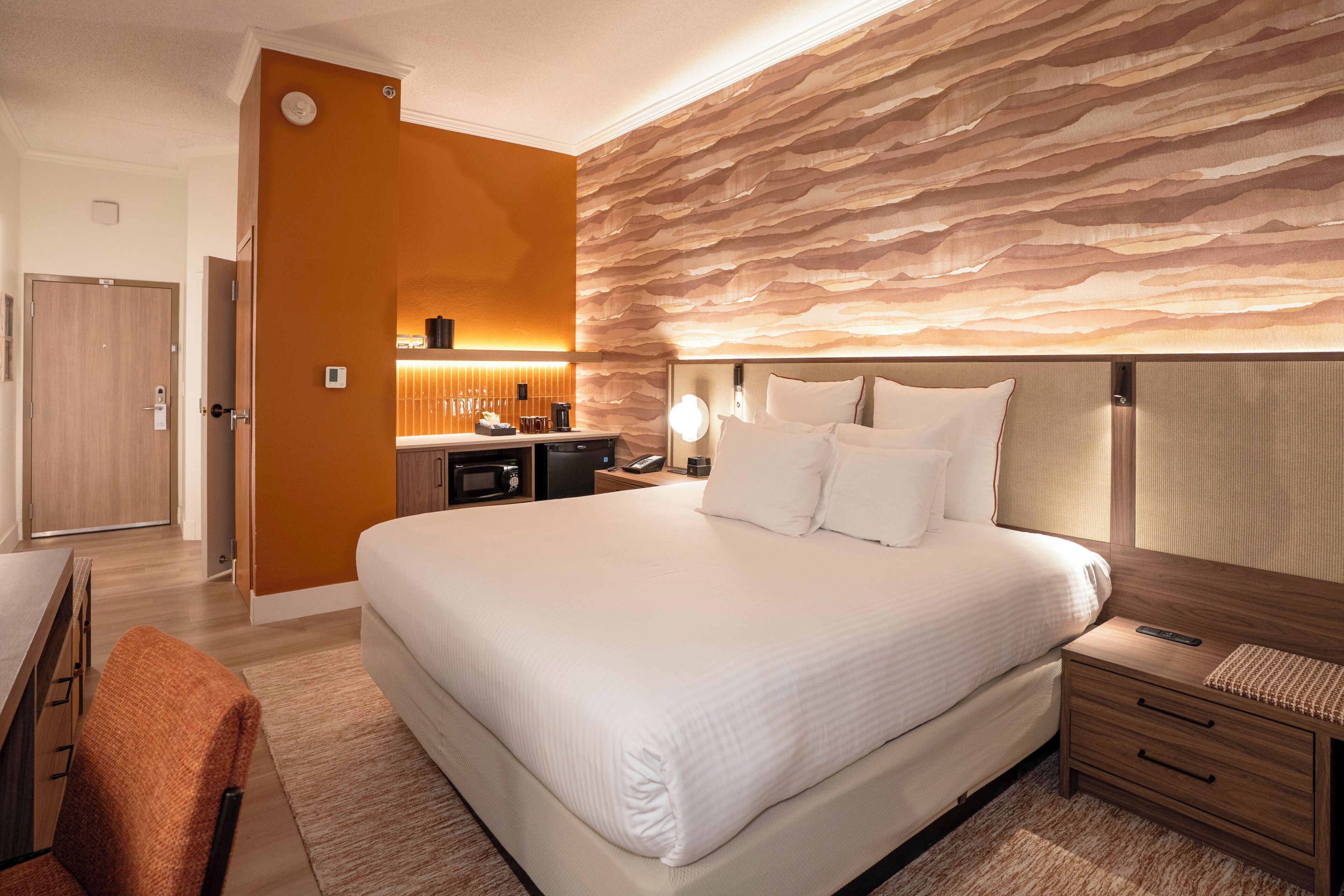 Une chambre d’hôtel avec un grand lit, des tables de chevet, un bureau et une salle de bain.