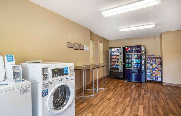 A laundry area with washing machines, a table, and vending machines.