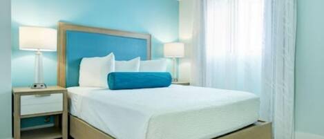 A hotel room with a single bed, two bedside tables, and a window with curtains.