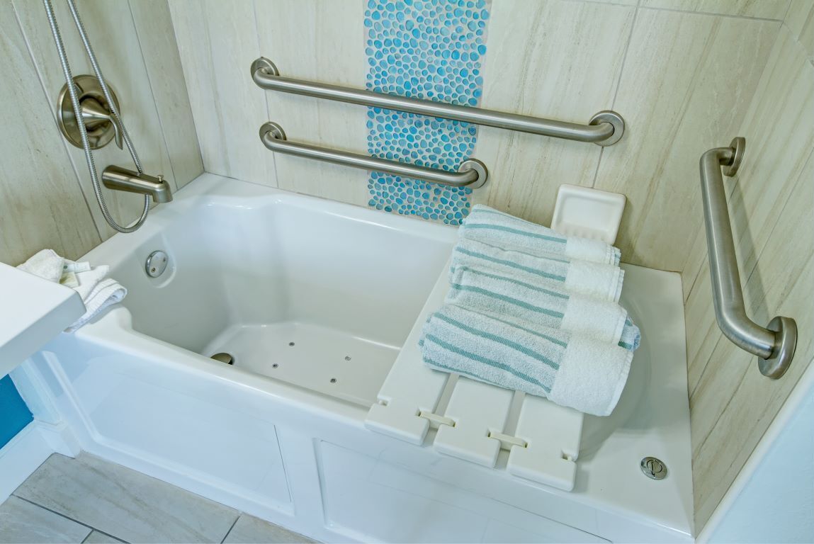 A white bathtub with a grab bar, a towel rack, and a showerhead.