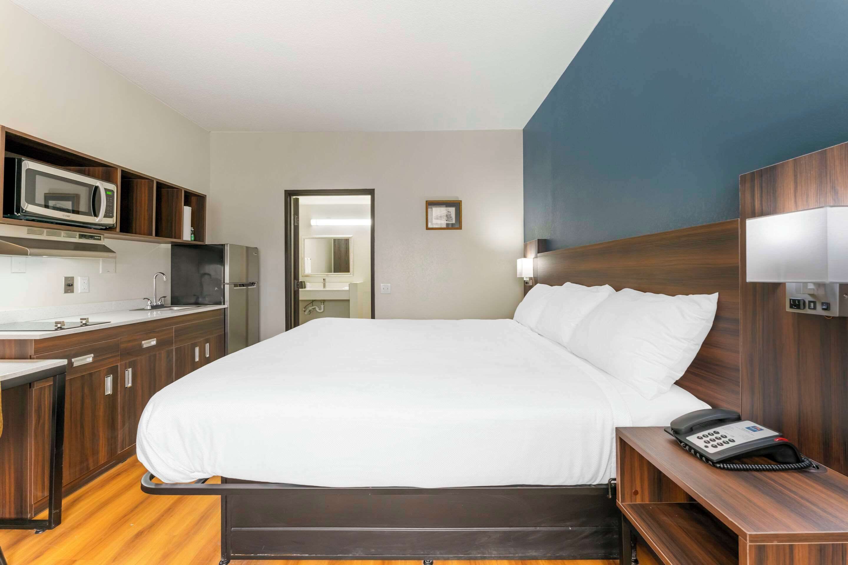 Una habitación de hotel con una cama, un escritorio con teléfono, microondas y refrigerador.