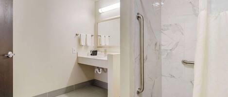 A modern bathroom with a marble shower, a sink with a mirror, and a towel rack.