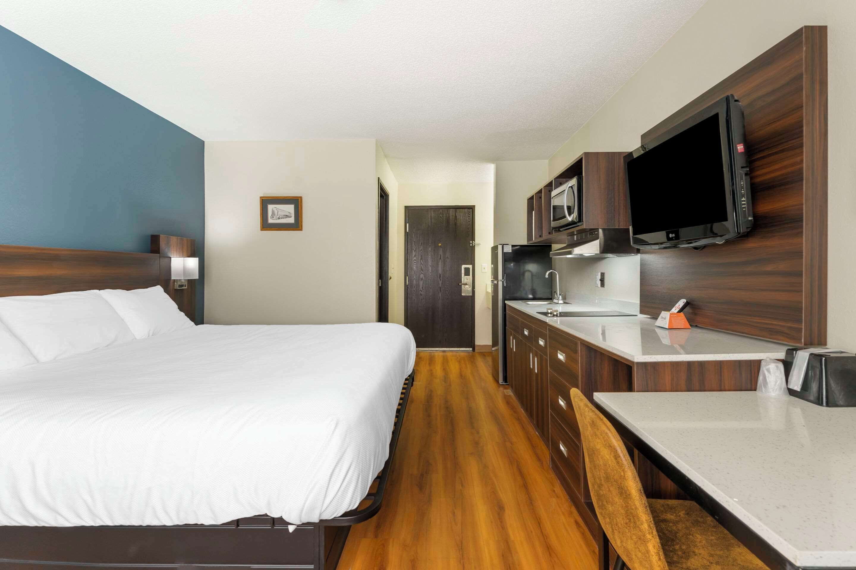 Ein Hotelzimmer mit Bett, Schreibtisch, Mikrowelle und Fernseher.