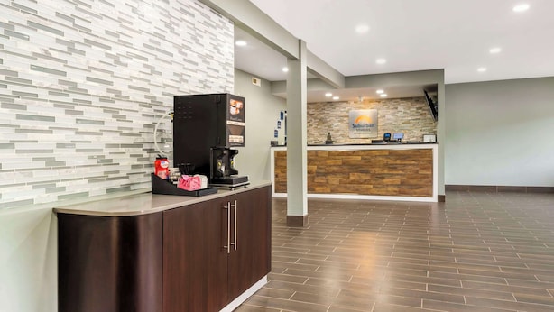 A reception area with a modern design, featuring a counter with a stone facade and a digital display. - Suburban Studios LaVale-Cumberland (Cumberland)