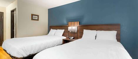 Two single beds with wooden headboards, white bedding, and bedside tables with lamps.