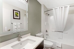 Ein modernes Badezimmer mit Waschbecken, Toilette und Dusche, alles in Weiß.