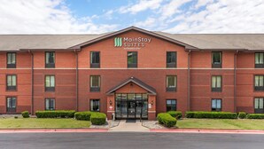 Un hotel MainStay Suites Extended Stay con fachada de ladrillo, ventanas grandes y cielo despejado.