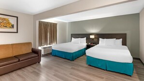 Habitación de hotel con dos camas, un sofá, una ventana con cortinas y un cuadro en la pared.