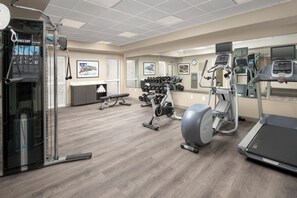Une salle de sport équipée de divers appareils d’exercice, notamment des tapis de course, des vélos d’appartement et des poids libres.