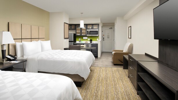 A hotel room with two beds, a kitchenette, a TV, and a desk. - Candlewood Suites Alexandria West by IHG (Alexandria)