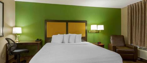 Habitación de hotel con una cama grande, dos lámparas de noche, un escritorio con lámpara, una silla y una ventana con cortinas.