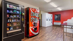 A vending machine area with snacks and beverages, a white laundry room, and a red wall.