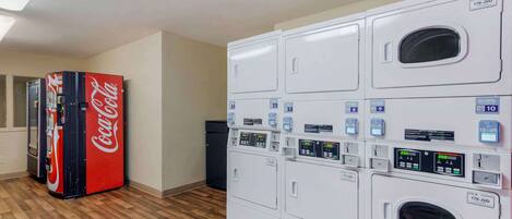 A laundry room with multiple washing machines and a Coca-Cola vending machine.