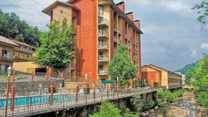 Ein mehrstöckiges Hotel mit Balkonen, einer Stein-Fassade und einer Brücke über einem Fluss.