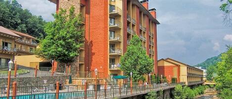 Et hotel med flere etager, altaner, en stenfassade og en bro over en flod.