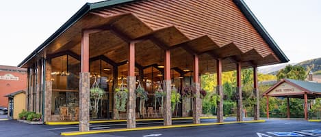 A covered outdoor area with stone pillars and hanging plants, leading to a building entrance.
