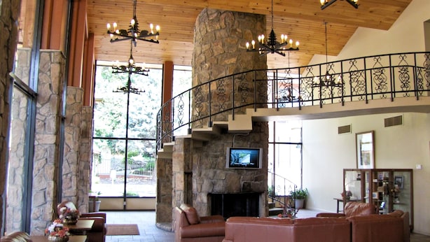 Eine großzügige Lobby mit Kamin aus Stein, Ledersofas und einem an der Wand befestigten Fernseher.