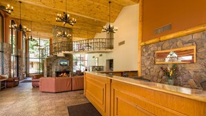 Eine großzügige Lobby mit Kamin aus Stein, einem Holzbüro und einem Balkon mit Steinbalustrade.