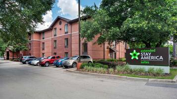 A brick building with a sign for Extended Stay America Suites. There are several cars parked in front.