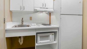 A compact kitchen with white cabinets, a stainless steel sink, a microwave, and a white refrigerator. - Extended Stay America Suites Richmond W Broad St Glenside S (Richmond)