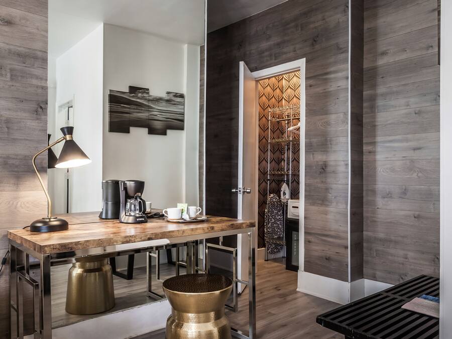 Um interior moderno com piso de madeira, um espelho grande, um espaço para café e uma parede estampada.