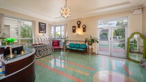 A reception area with a curved desk, a green sofa, and a bicycle rack. - Century Hotel (Miami Beach)