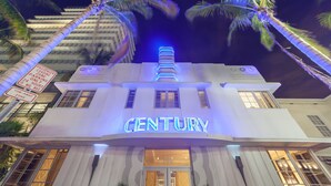 A hotel named 'CENTURY' with a neon sign, a parking sign indicating a 15-minute zone, and palm trees in the foreground. - Century Hotel (Miami Beach)