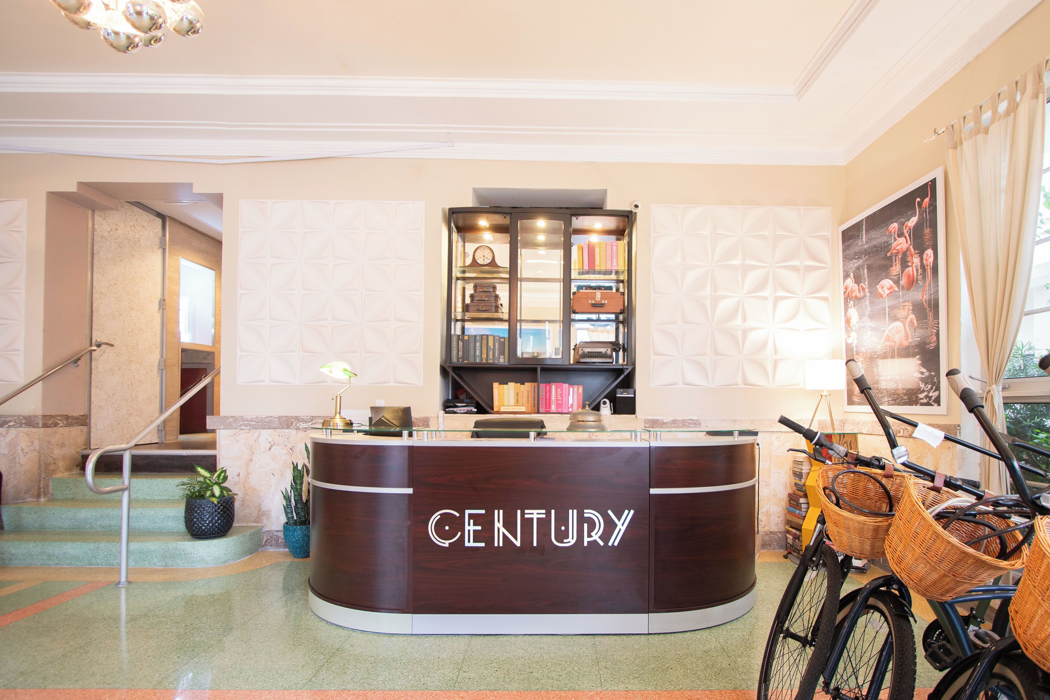 A reception desk labeled "CENTURY" with a bookshelf, potted plants, and a bicycle with baskets.