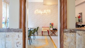 A hotel lobby with a marble reception desk, a neon sign reading "Casting 1939", and a Coca-Cola cooler. - Century Hotel (Miami Beach)