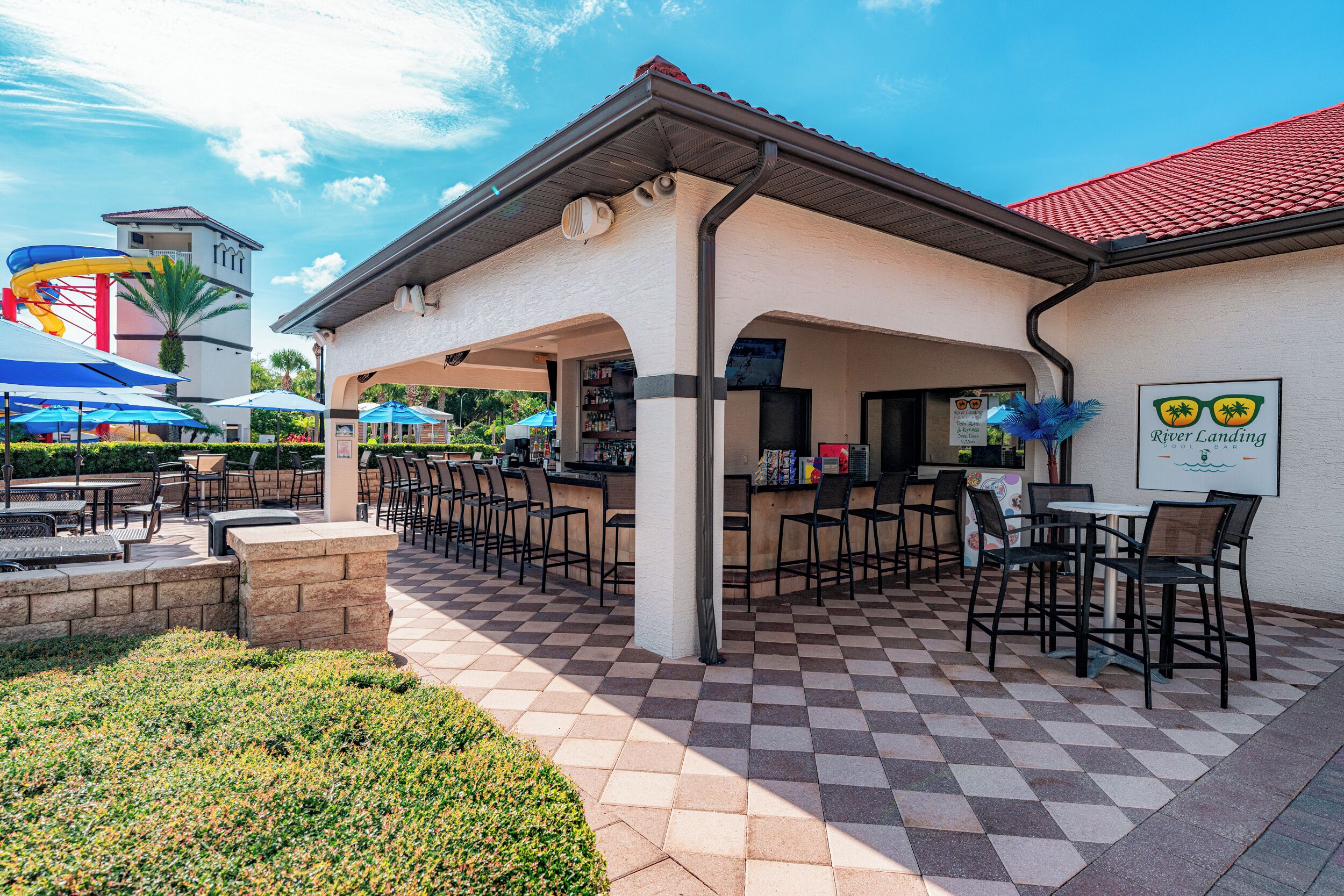 An outdoor patio area with checkered flooring, outdoor seating, and a bar area.