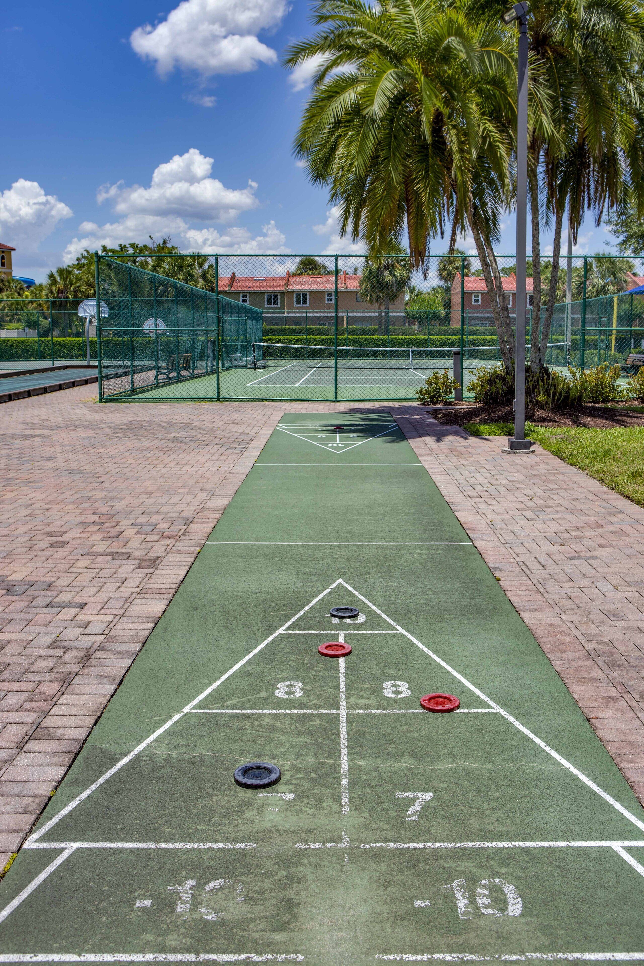 A shuffleboard court with numbered scoring areas and a green fence surrounding it.