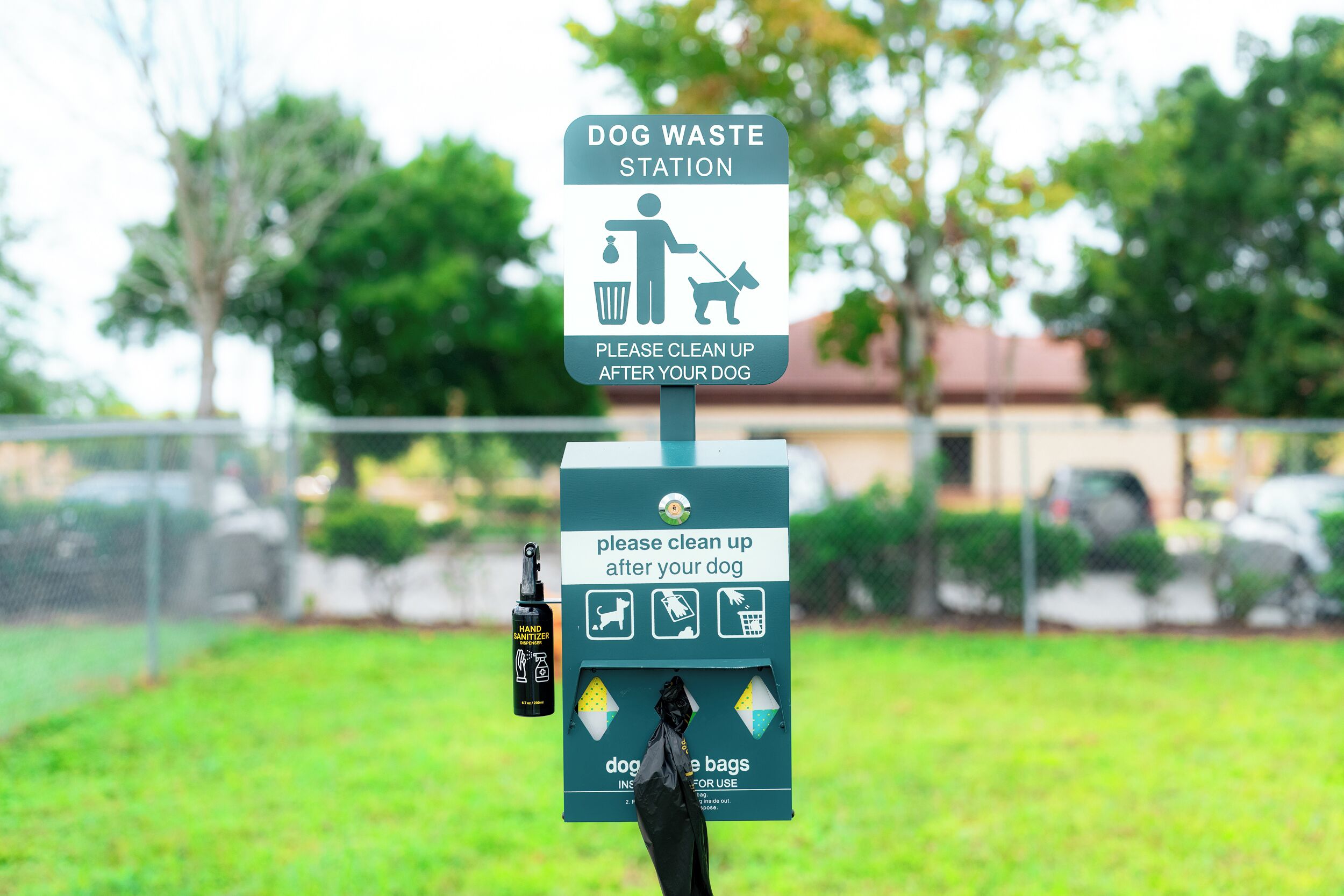 Un poste de collecte des excréments canins comprenant un panneau indiquant qu’il faut ramasser les déjections de son chien, un distributeur de gel hydroalcoolique et des sacs pour ramasser les excréments canins.