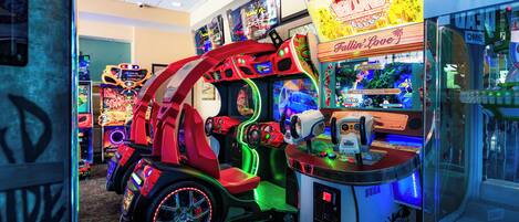 A row of arcade machines with neon lights and a racing game in the center.