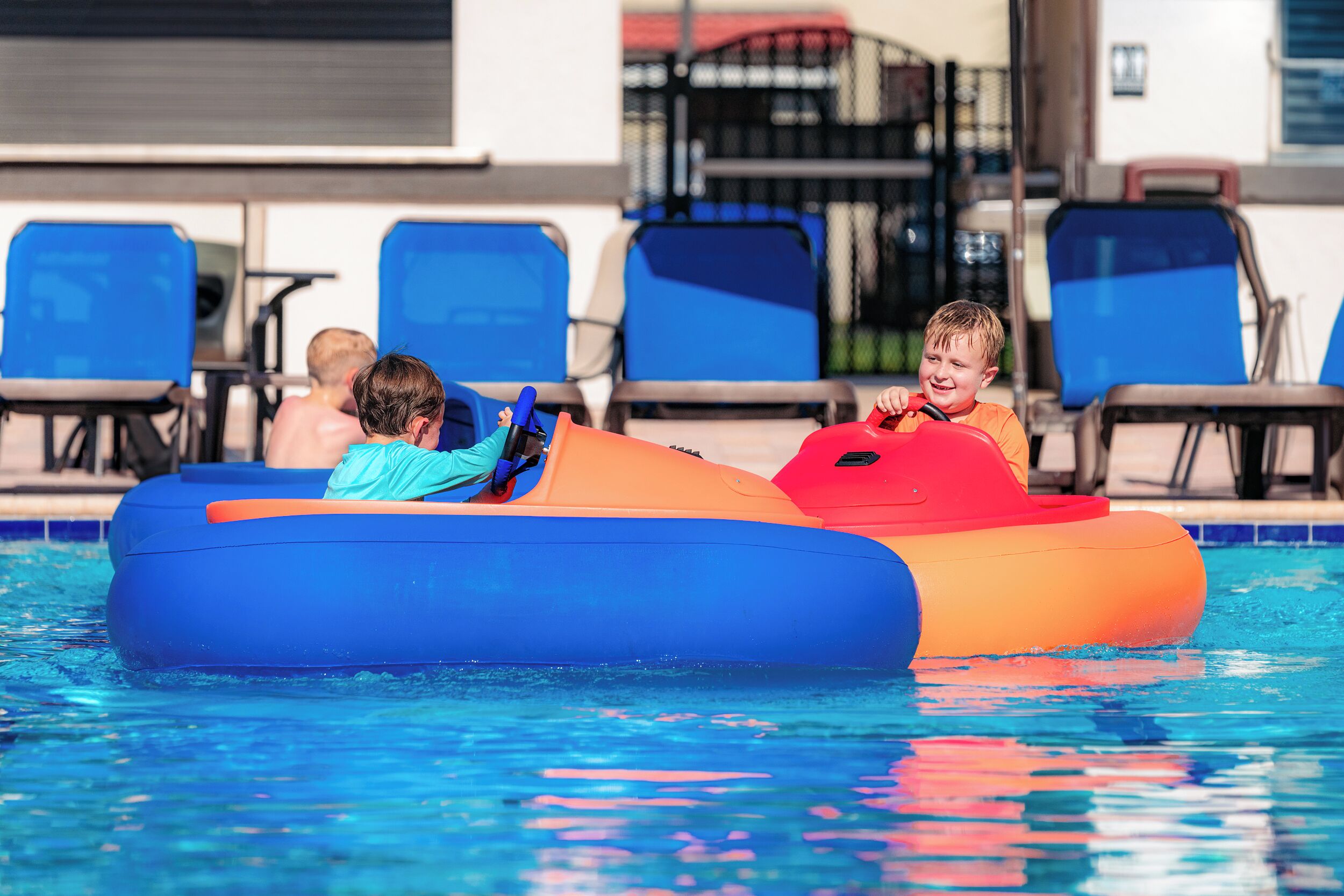 A swimming pool with inflatable rafts and blue lounge chairs.