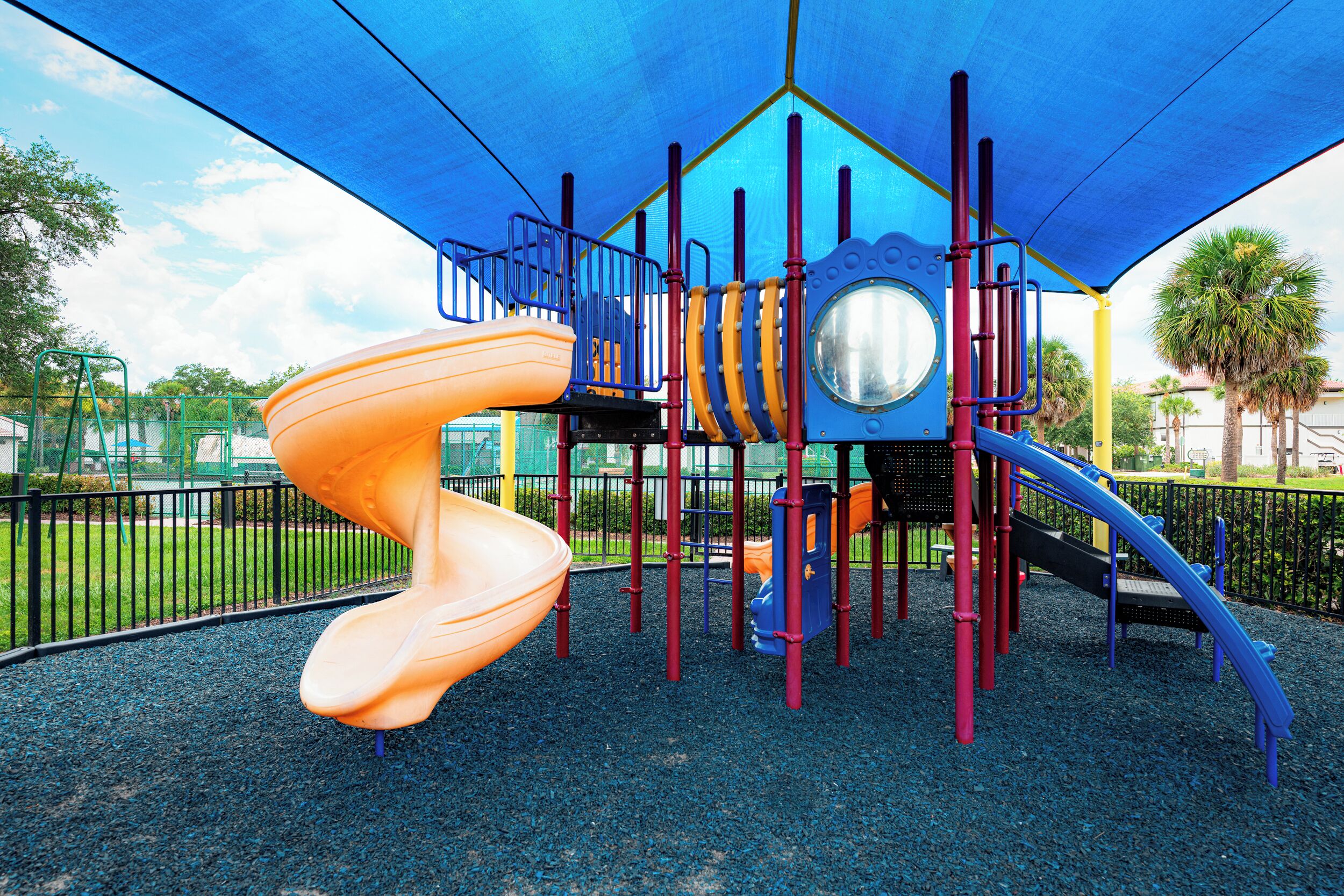 A playground with a spiral slide, climbing structures, and a covered play area.