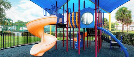 A playground with a spiral slide, climbing structures, and a covered play area.