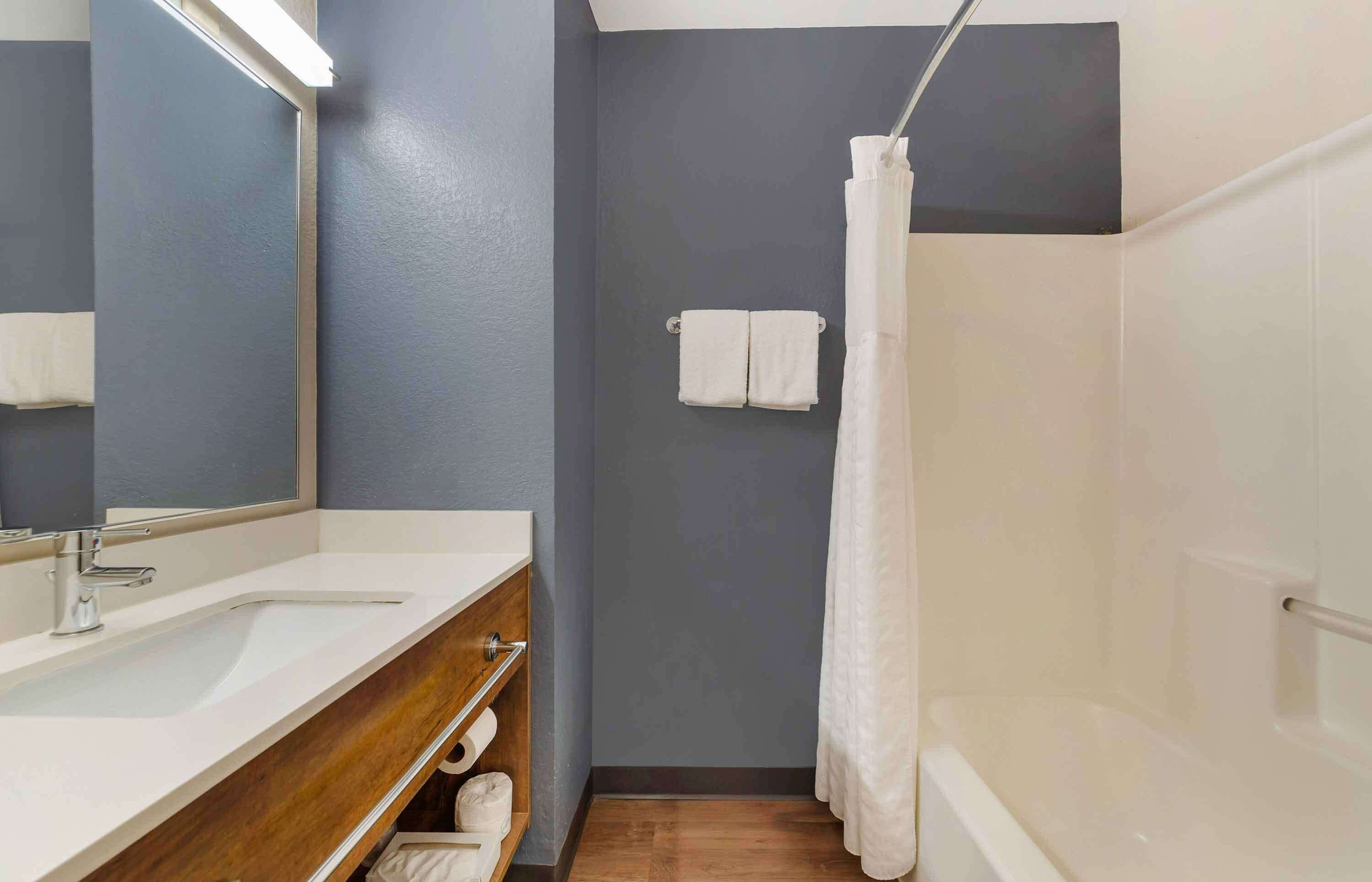 A bathroom with a white sink, mirror, and shower curtain.