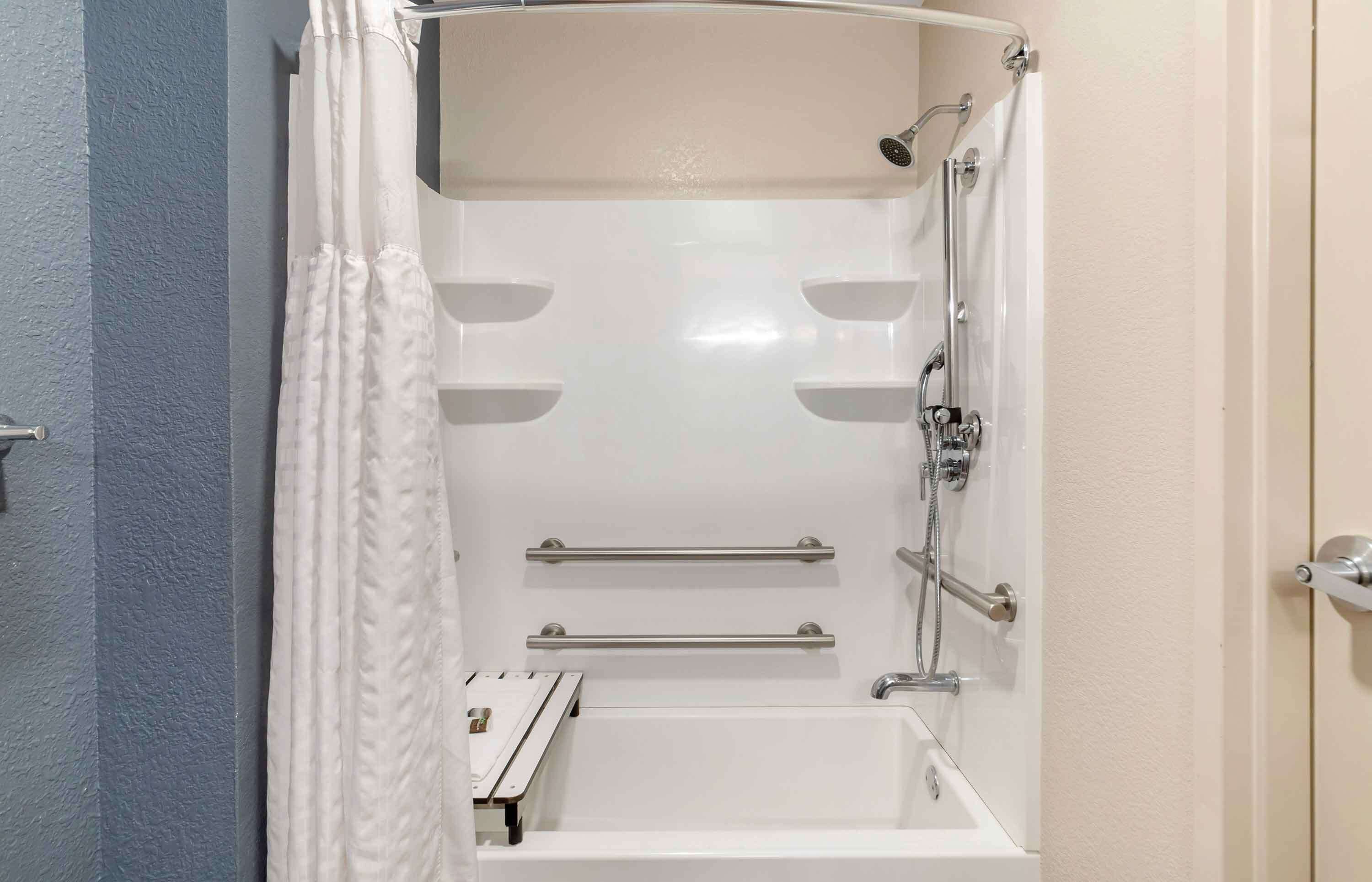 A modern bathroom with a bathtub, shower, and two towel bars.