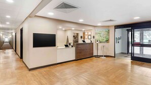 Un espace d’accueil moderne avec un plancher en bois, un comptoir d’accueil, un téléviseur à écran plat, une machine à café et une carte affichée au mur.